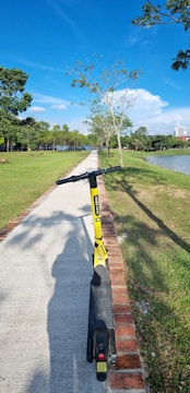 Bright yellow Scoot Scoot electric scooter parked near a scenic New England trail.