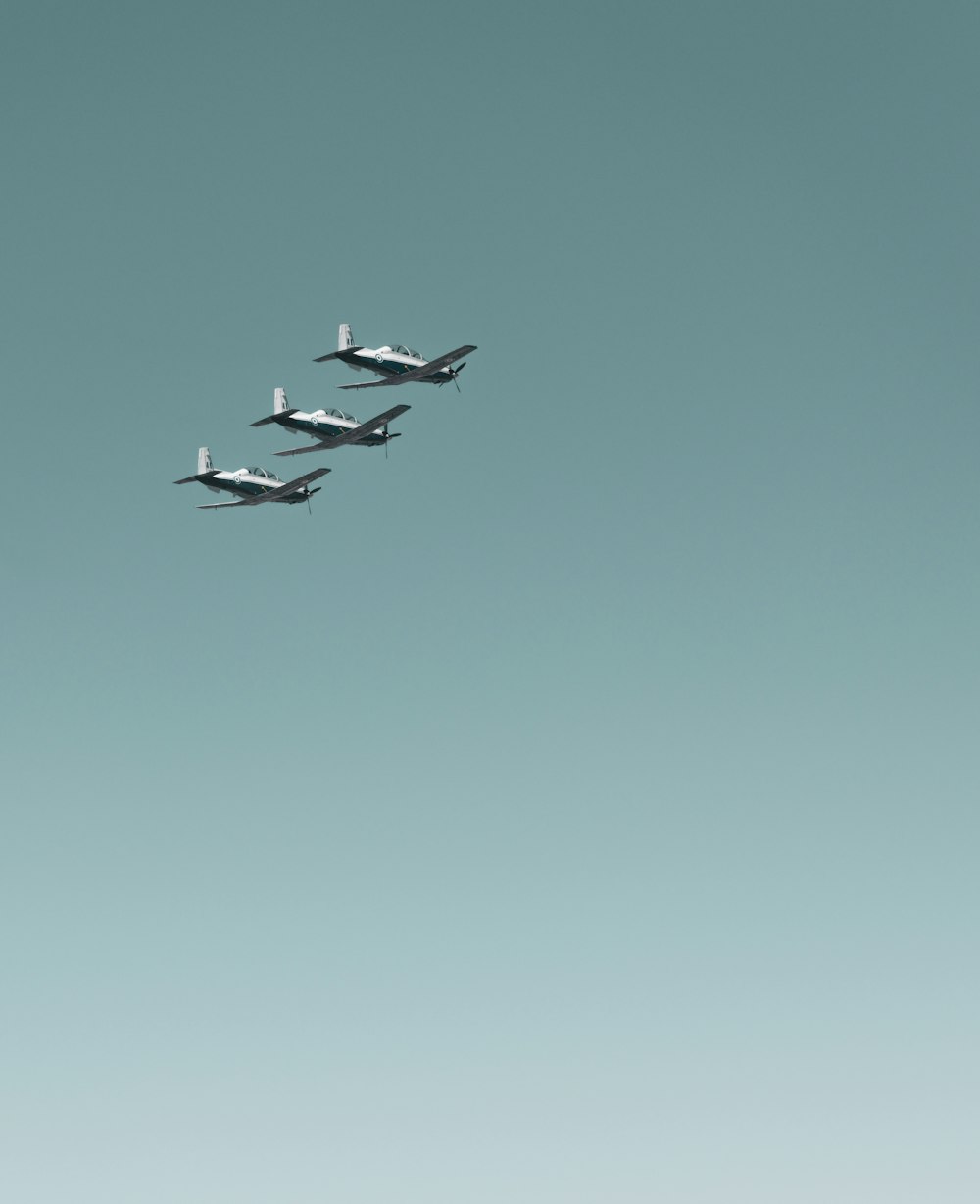 a group of four airplanes flying through a blue sky