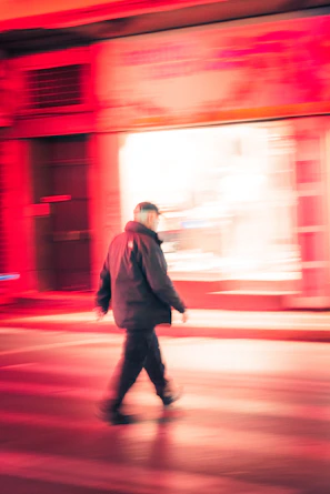 A model wearing a sleek, breathable jacket walking through a bustling urban street at dusk.