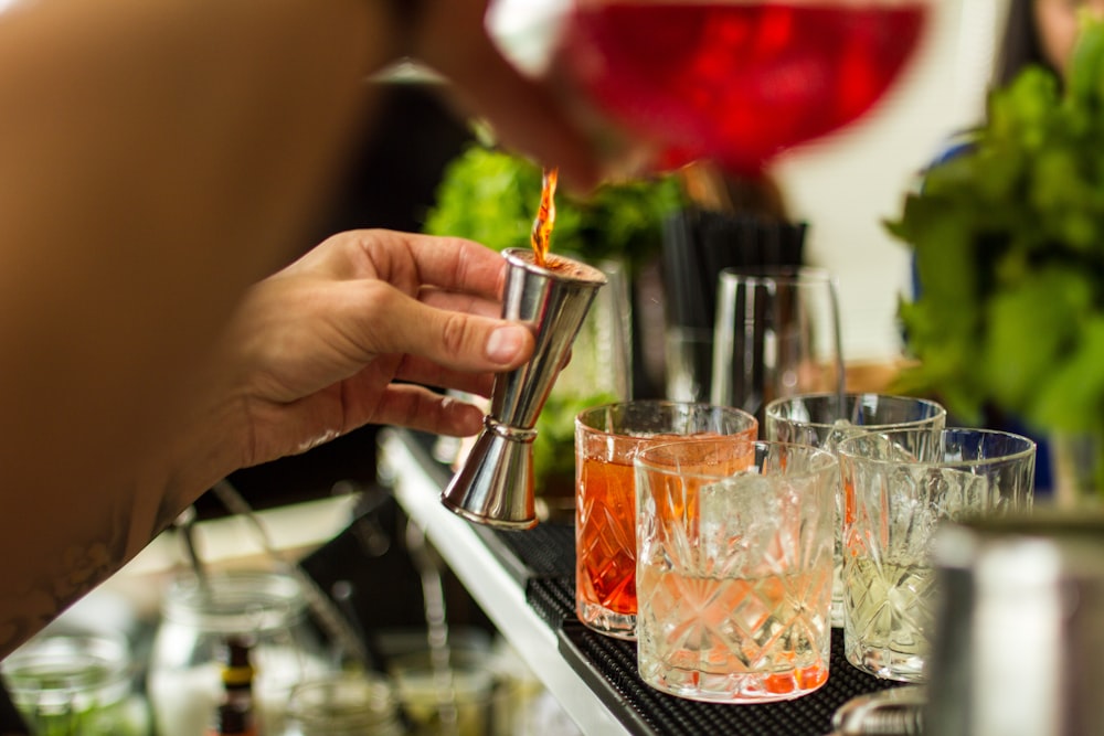 a person is pouring a drink into a glass