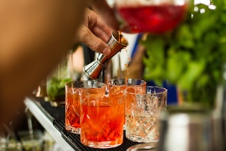 a person pouring a drink into glasses on a bar