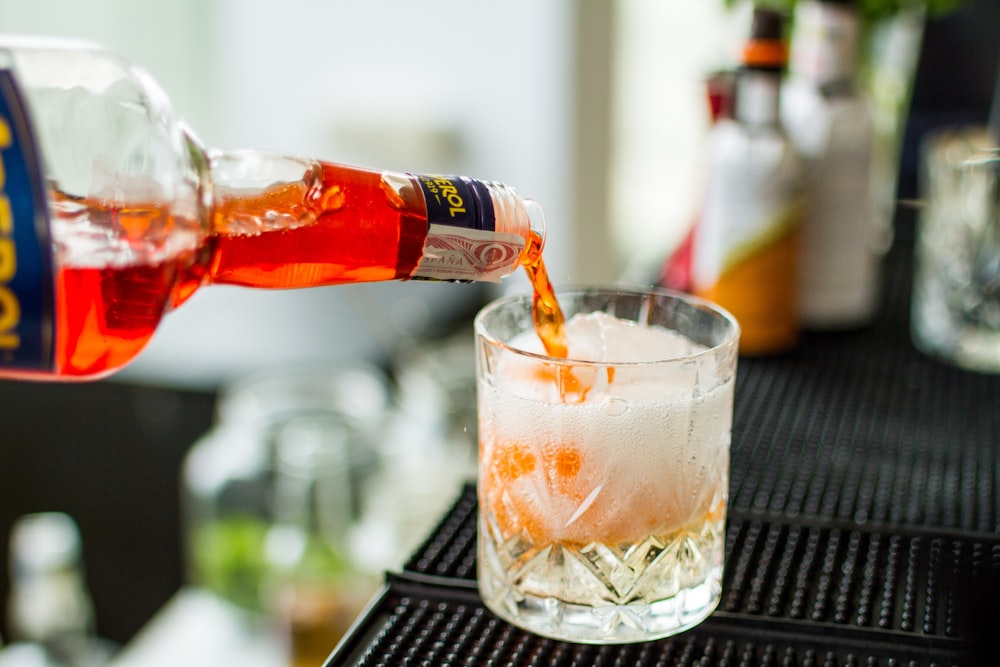 a person pouring a drink into a glass