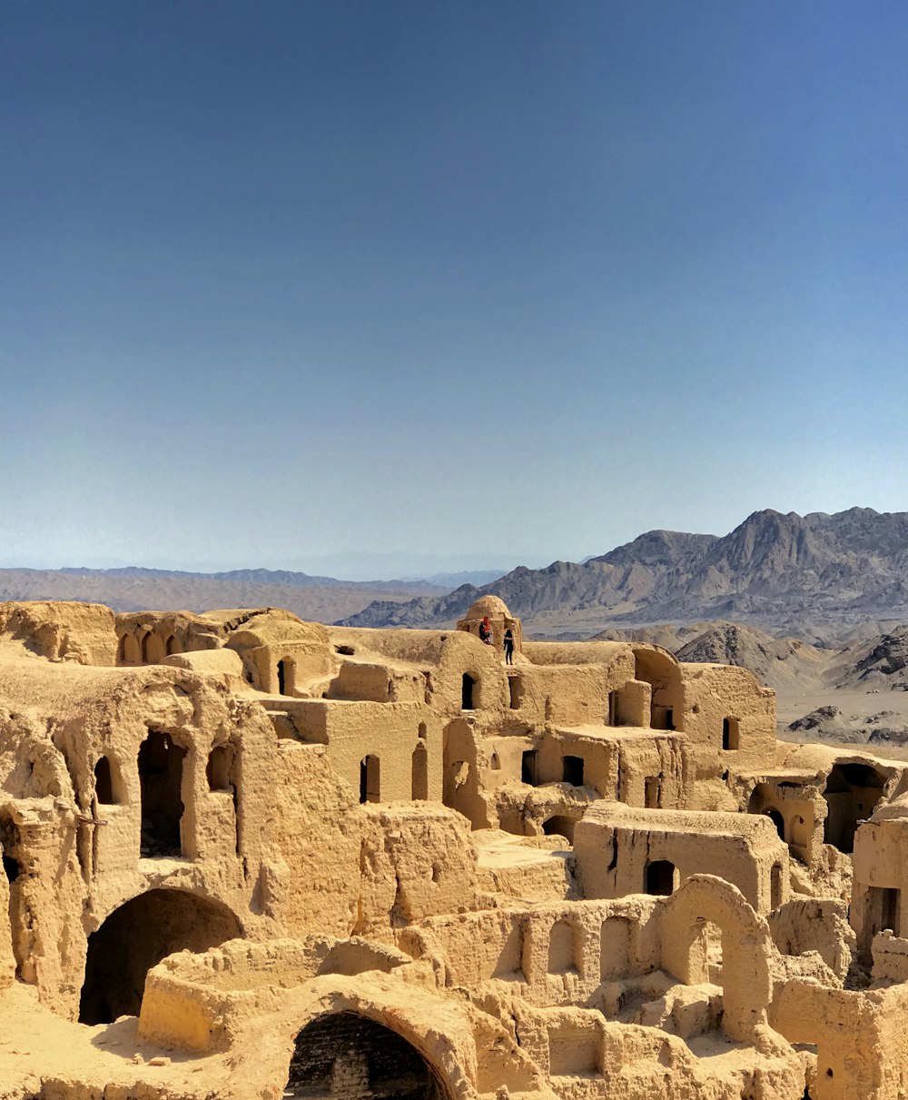 a group of buildings in the desert with mountains in the background