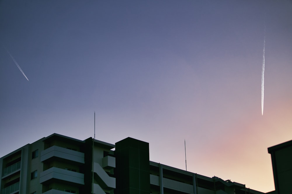 an airplane is flying over a building at sunset