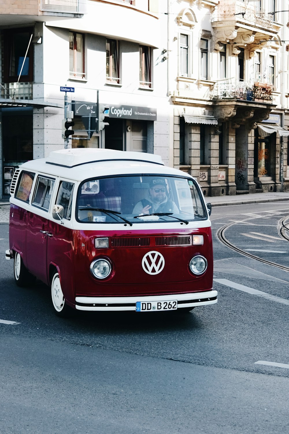 a red and white van driving down a street next to tall buildings