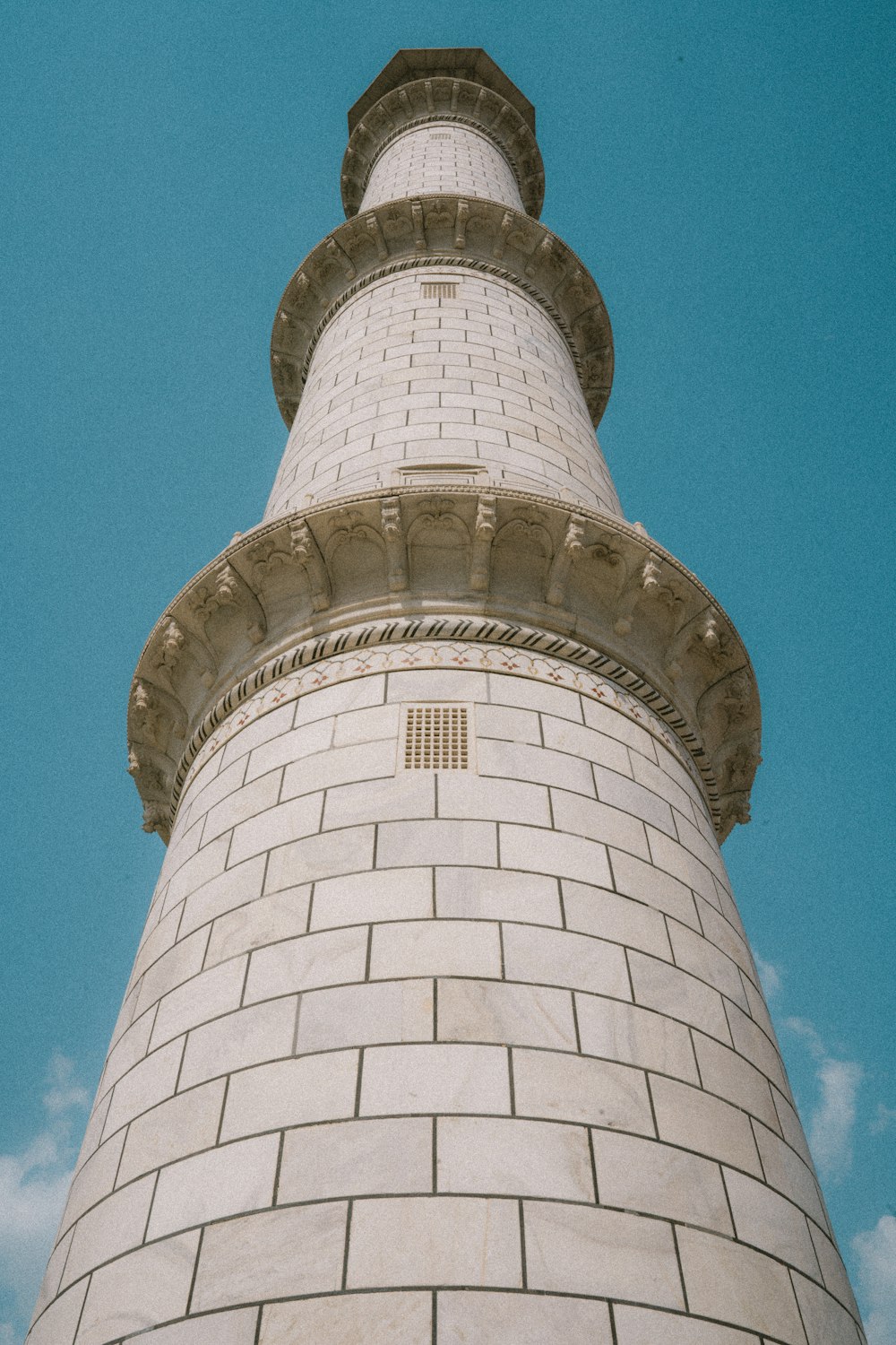 a tall white brick tower with a clock on it's side