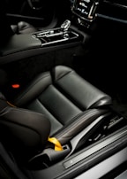 A sleek black car interior featuring custom-made automotive covers matching the brand's blue and yellow palette