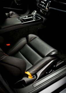 A sleek black car interior featuring custom-made automotive covers matching the brand's blue and yellow palette