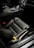 A sleek and modern car interior featuring black leather seats with a distinctive yellow seatbelt. The center console is designed with a crystal gear lever and polished metallic accents, creating a luxurious atmosphere. The dash includes a digital display with illuminated controls, highlighting a focus on technology and style.