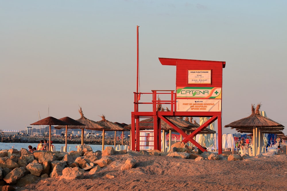 a red lifeguard tower sitting on top of a sandy beach