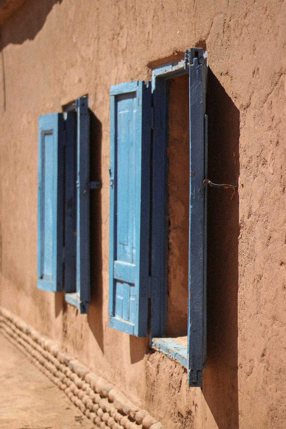 two blue shutters on a tan building