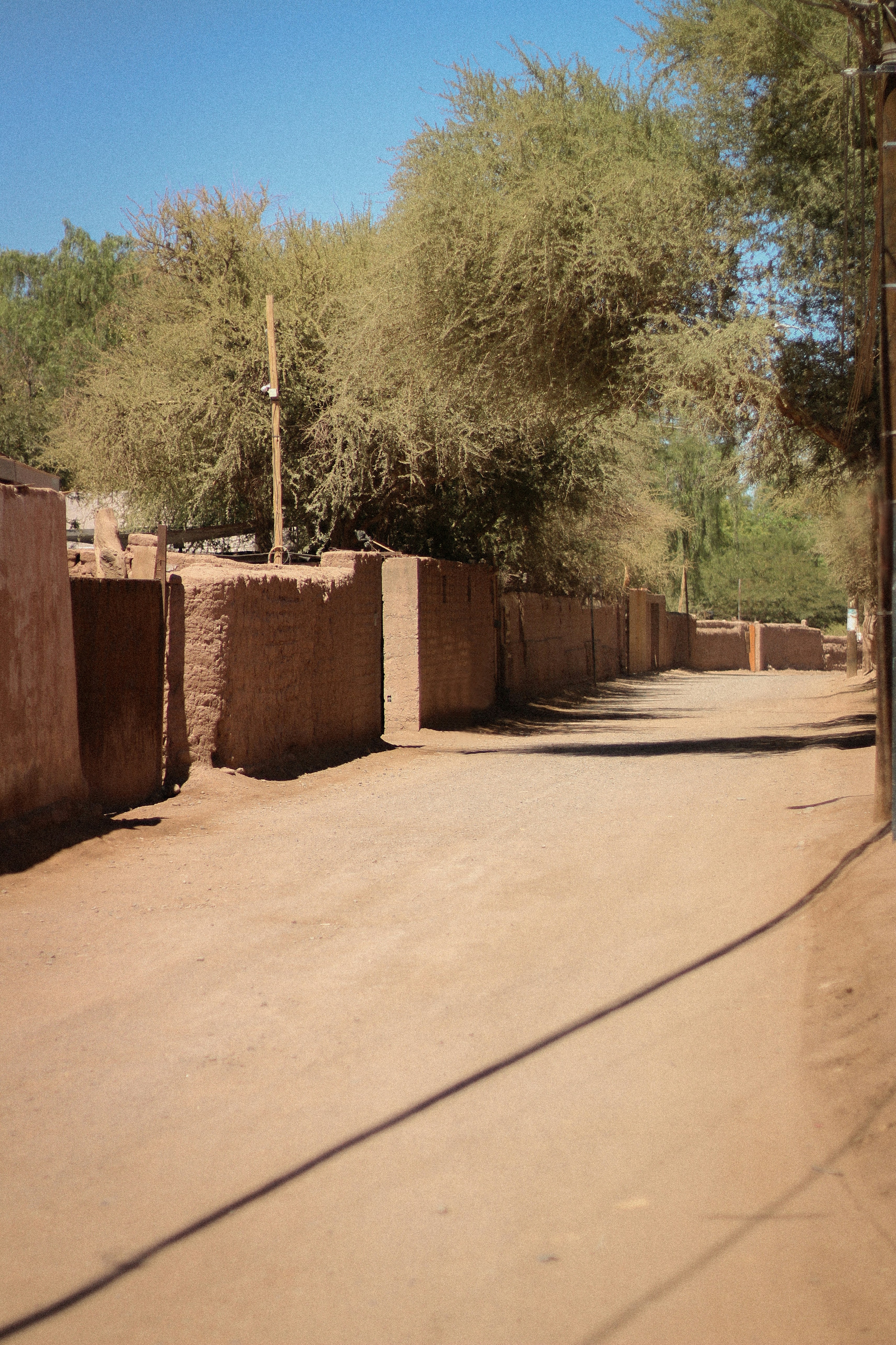 a dirt road with a building and trees in the background