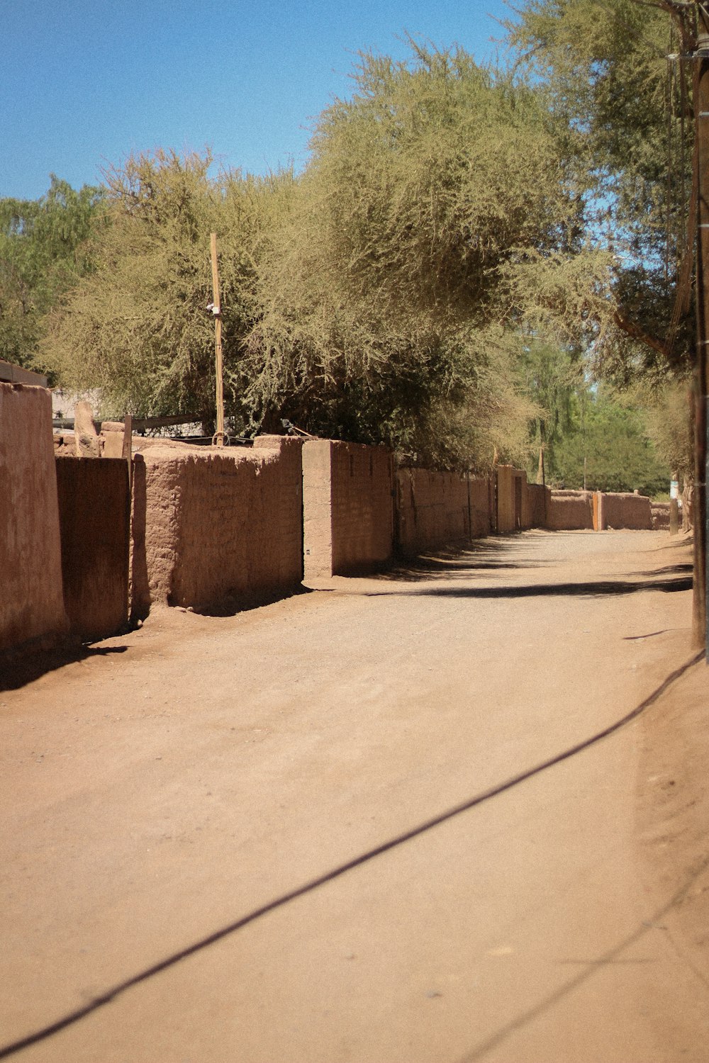 a dirt road with a building and trees in the background