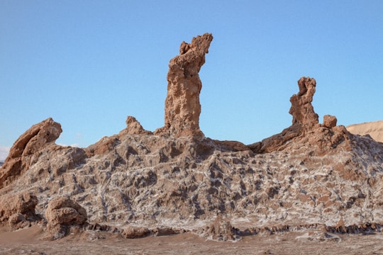 A geologist examining rock samples in a rugged mining terrain under a clear sky.