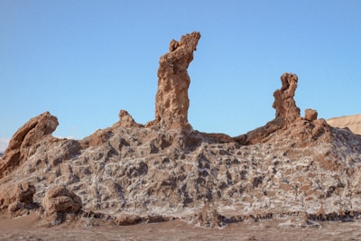 A geologist in the field examining rock formations with modern instruments under a clear sky.