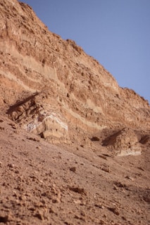 Geologist analyzing rock formations with a rugged mountain backdrop.