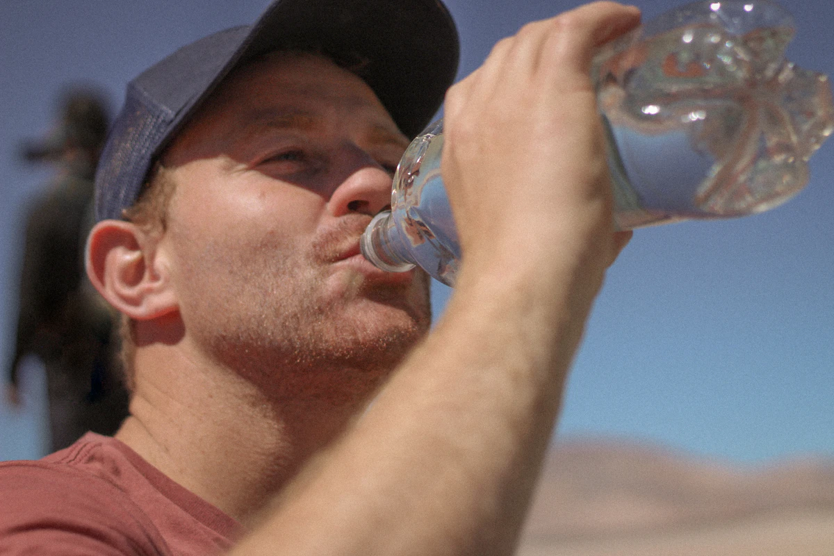 Man drinking water from a plastic bottle outdoors, illustrating everyday endocrine disruptor exposure and testosterone.