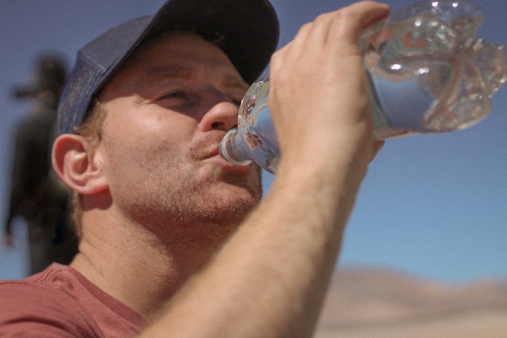 a man drinking water out of a bottle