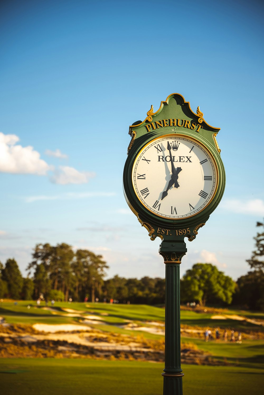 a clock on a pole in the middle of a golf course