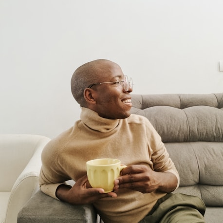 a man sitting on a couch holding a cup