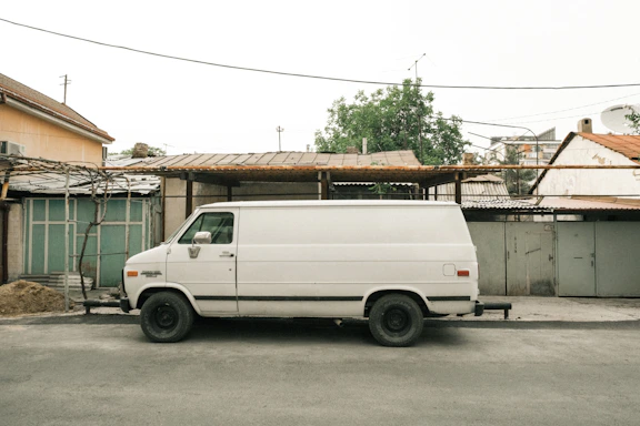 A friendly driver standing next to a clean, white cargo van in a sunny Charlotte neighborhood.