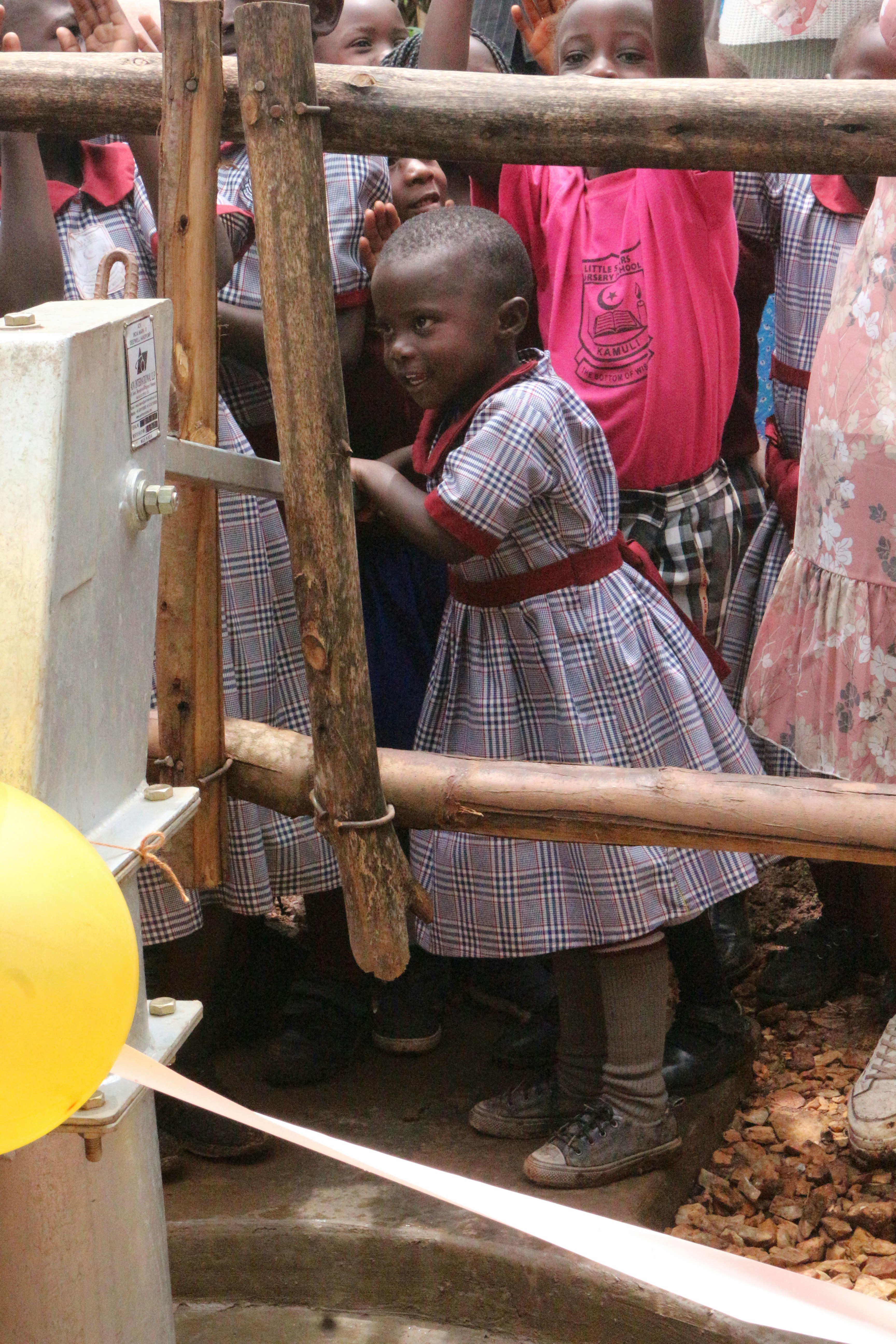a group of children standing around a water pump