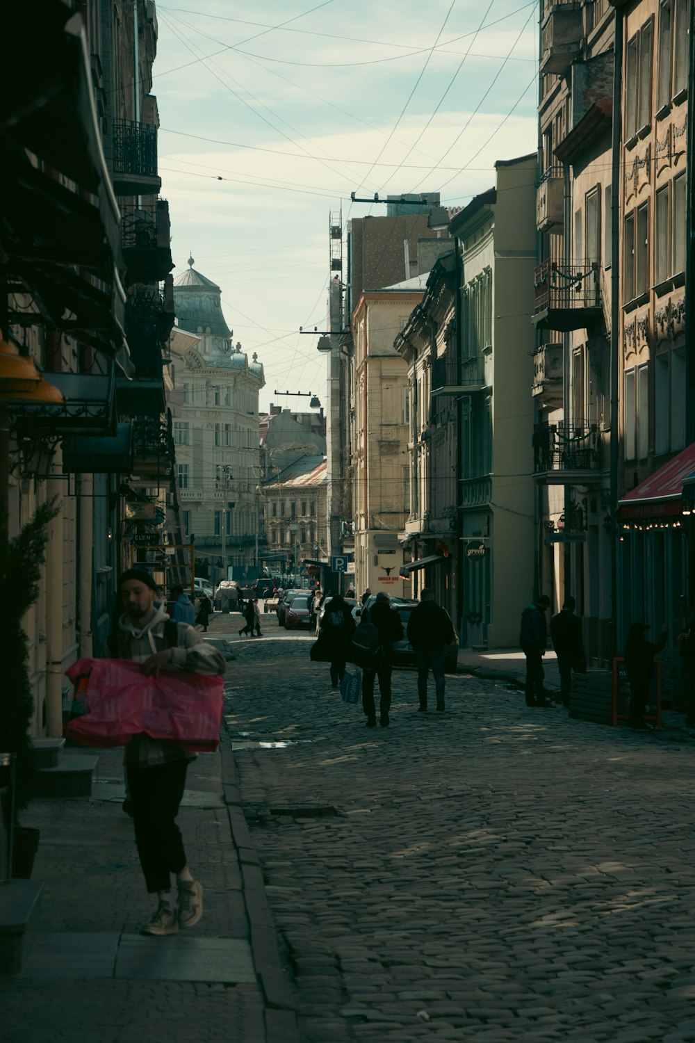 a woman walking down a street holding a pink umbrella