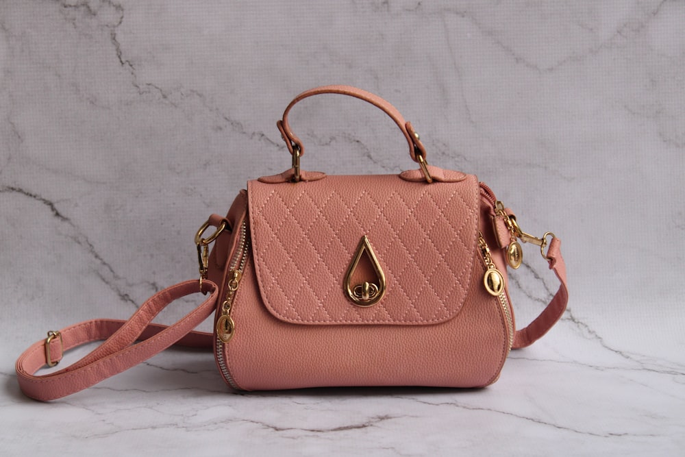 a pink handbag sitting on top of a marble counter