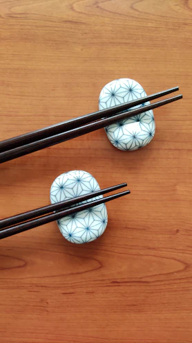 Close-up of elegant stainless steel chopsticks resting on a minimalist ceramic holder.