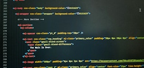 A computer screen displaying code with HTML-like tags and inline CSS styles. The code featured includes elements such as mj-body, mj-wrapper, and mj-text with specific styling for background colors, padding, alignment, and text content. Notable text within the code includes 'The Wait Is Over.'