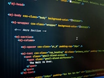 HTML code displayed on a computer screen, featuring elements such as 'mj-body', 'mj-wrapper', and 'mj-text'. The code includes CSS classes for styling purposes, indicating colors with hex codes like '#151629'. A comment suggests this section is the 'Hero Section'.