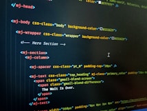 HTML code displayed on a computer screen, featuring elements such as 'mj-body', 'mj-wrapper', and 'mj-text'. The code includes CSS classes for styling purposes, indicating colors with hex codes like '#151629'. A comment suggests this section is the 'Hero Section'.