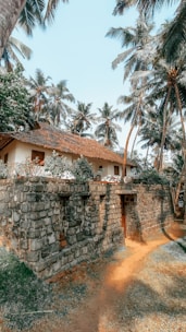 Cozy rustic finca with stone walls and olive trees under a clear blue sky.