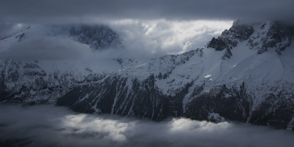 a mountain covered in snow under a cloudy sky