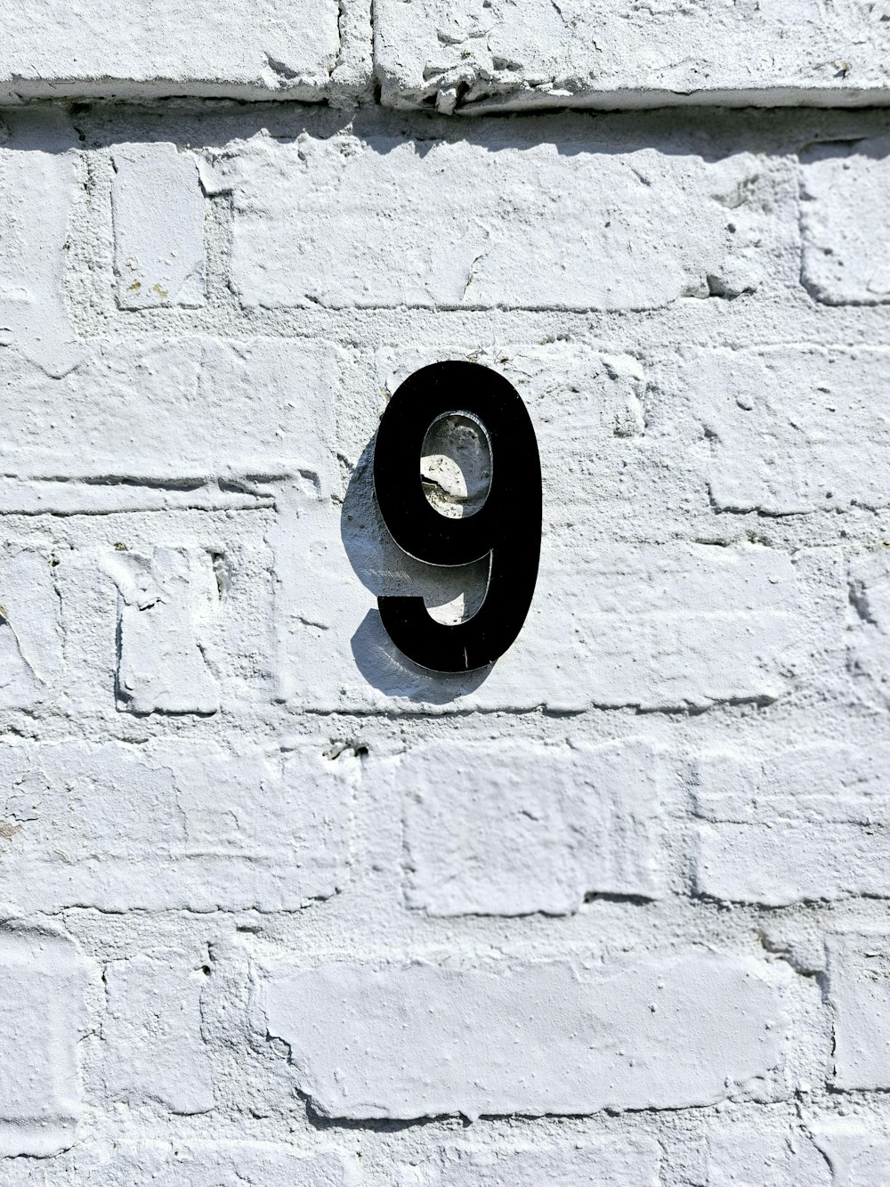 una pared de ladrillo blanco con un número nueve negro