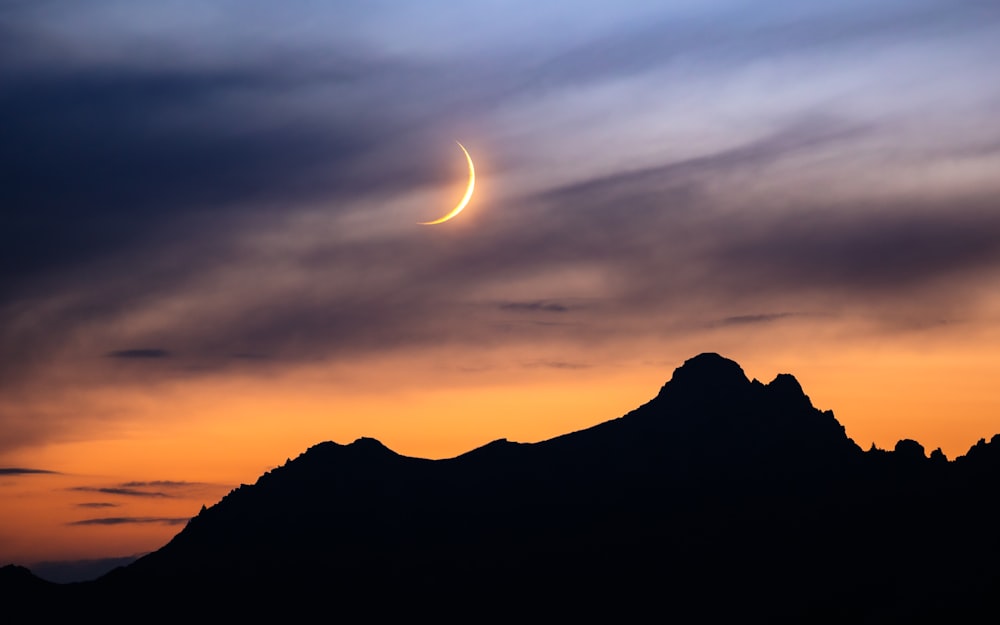 a crescent is seen in the sky over a mountain