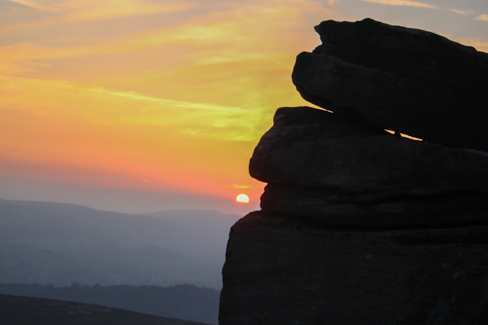 a stack of rocks with the sun setting in the background