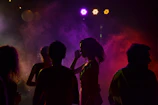 Wide shot of a nighttime party scene with vibrant lighting and energetic crowd.
