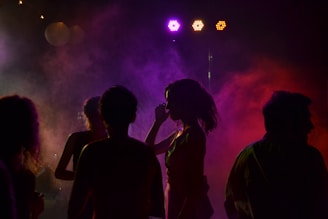 A videographer filming a lively party with colorful lights and joyful guests.