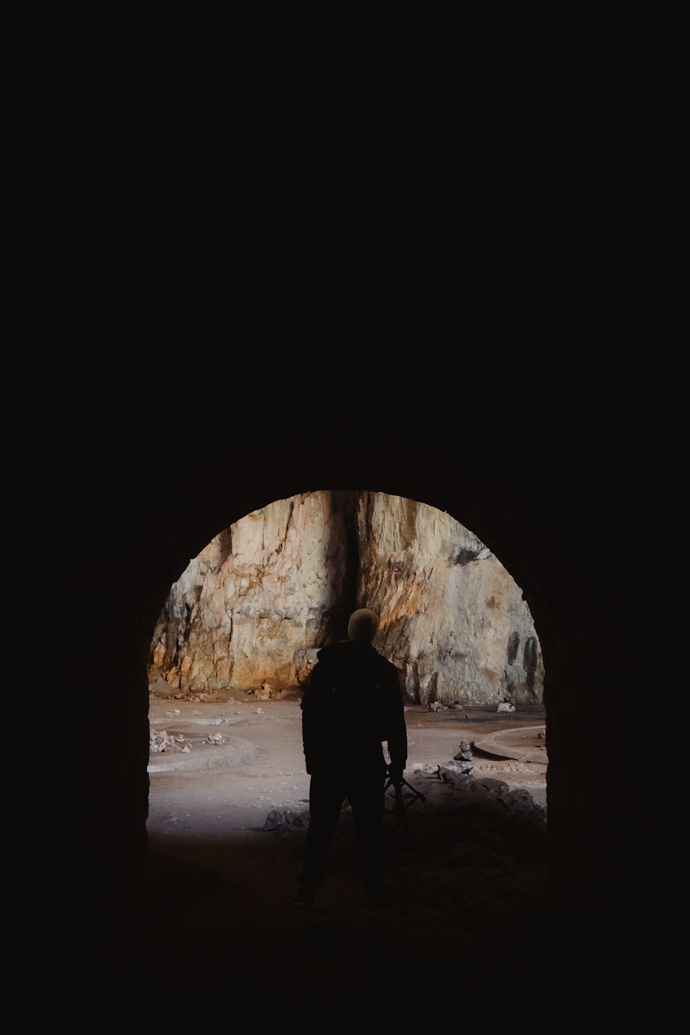 a man standing in a dark tunnel with his back to the camera