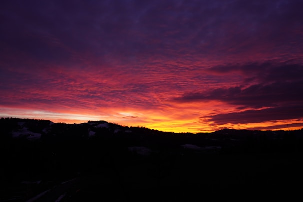 A dramatic landscape featuring a sunset over rolling hills with magenta hues.