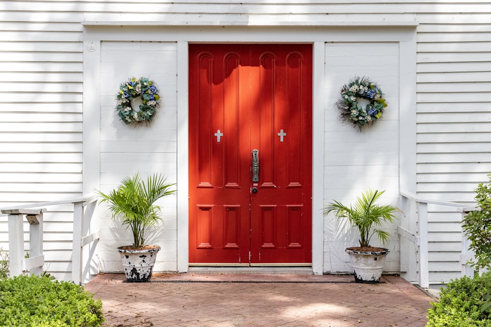 a red front door with two wreaths on it