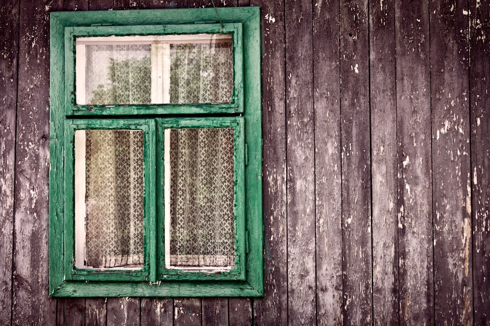 a green window sitting on the side of a wooden building