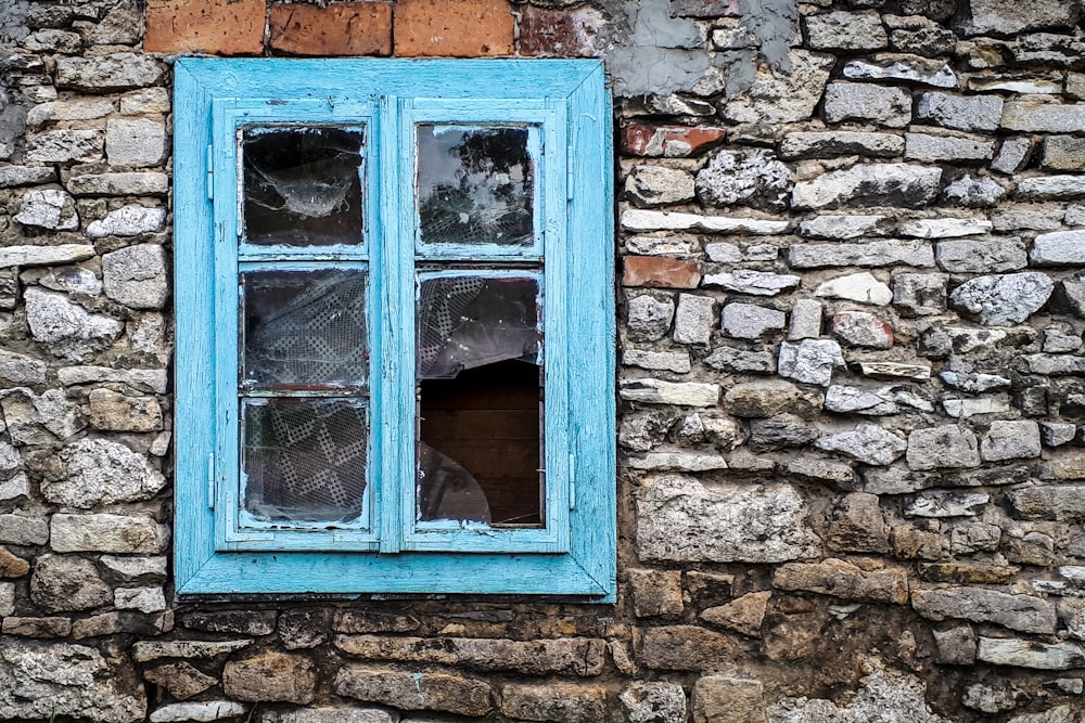 a window with a broken glass on a stone wall