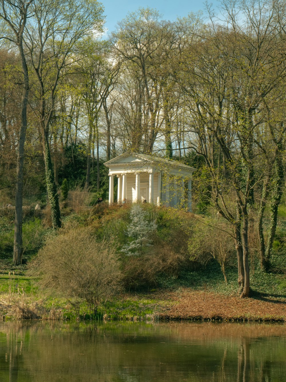 a gazebo sitting on top of a lush green hillside next to a lake