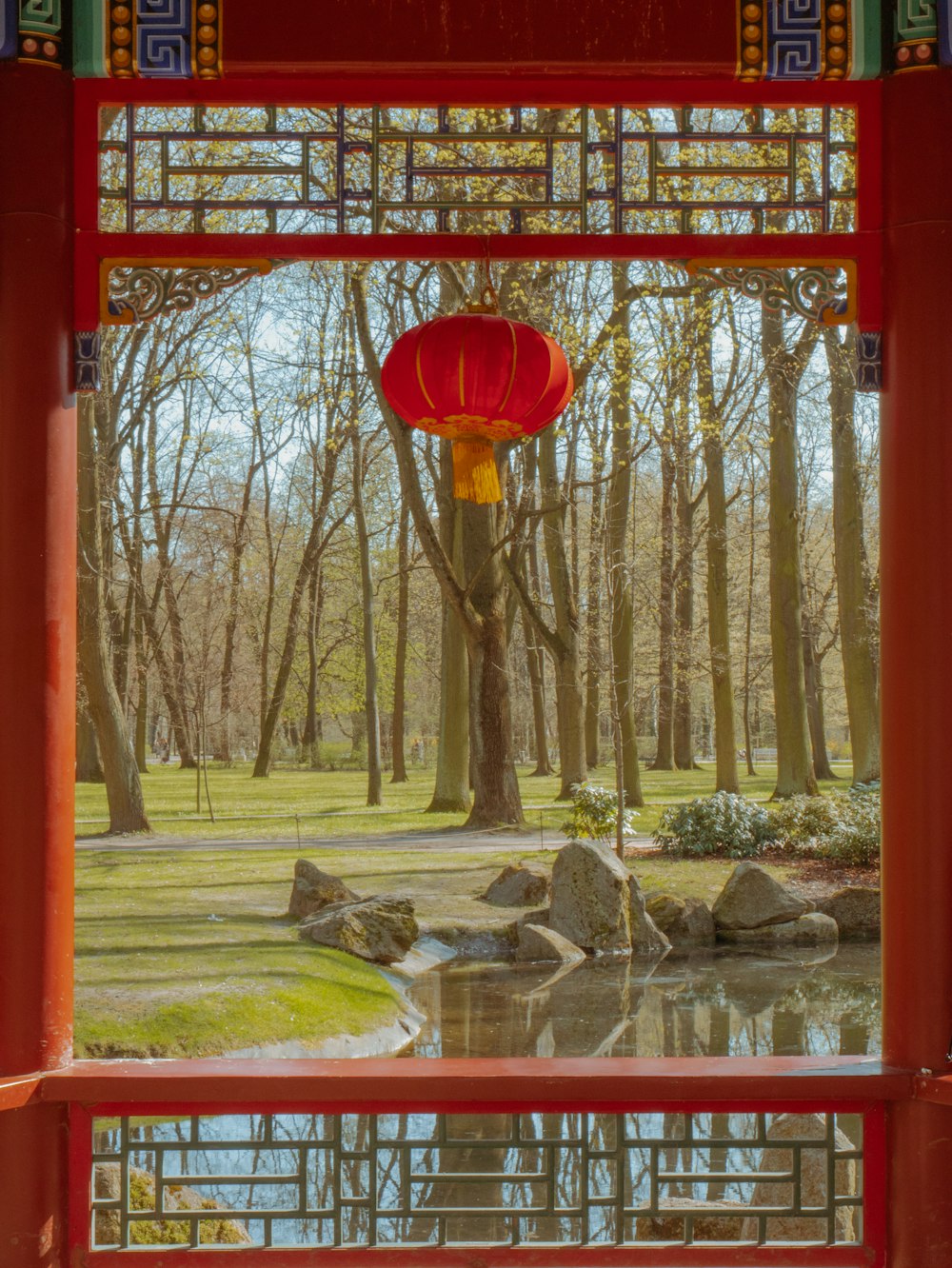 a red lantern hanging over a pond in a park