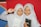 Two young girls wearing white hijabs are smiling. The girl on the left is holding a book with 'jeda' on the cover, while the girl on the right is holding a book with '00.00' on the cover. They are standing in front of a colorful backdrop featuring red, blue, and yellow sections.