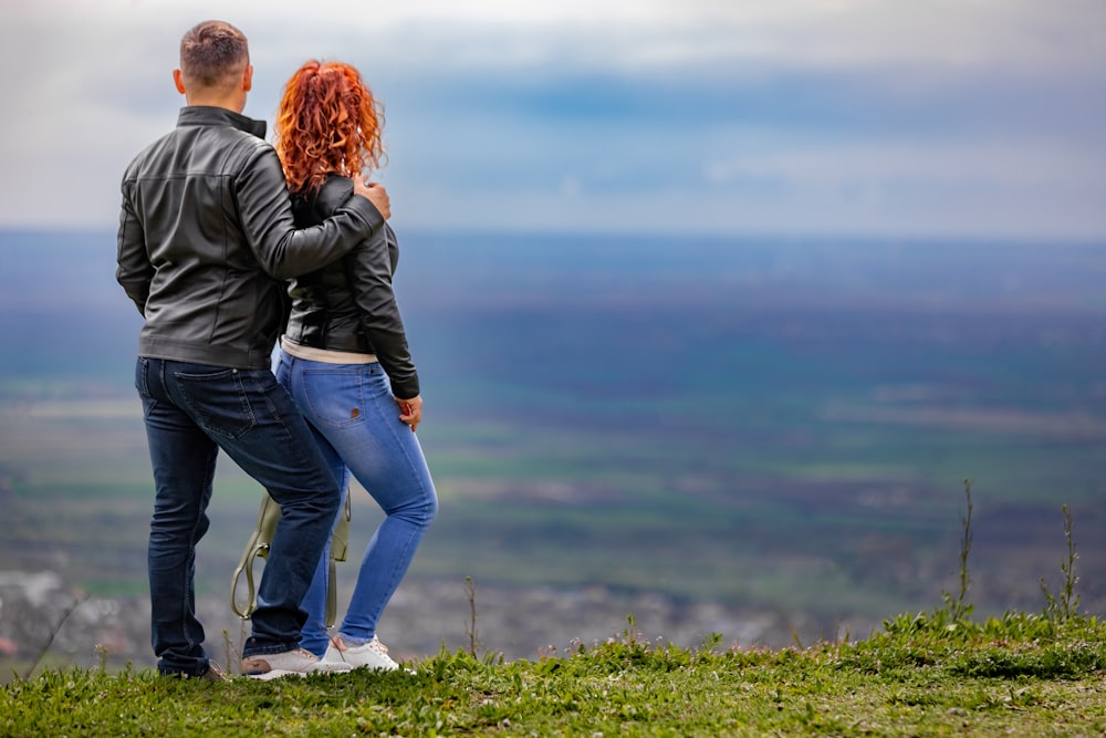 a man and a woman standing on top of a hill