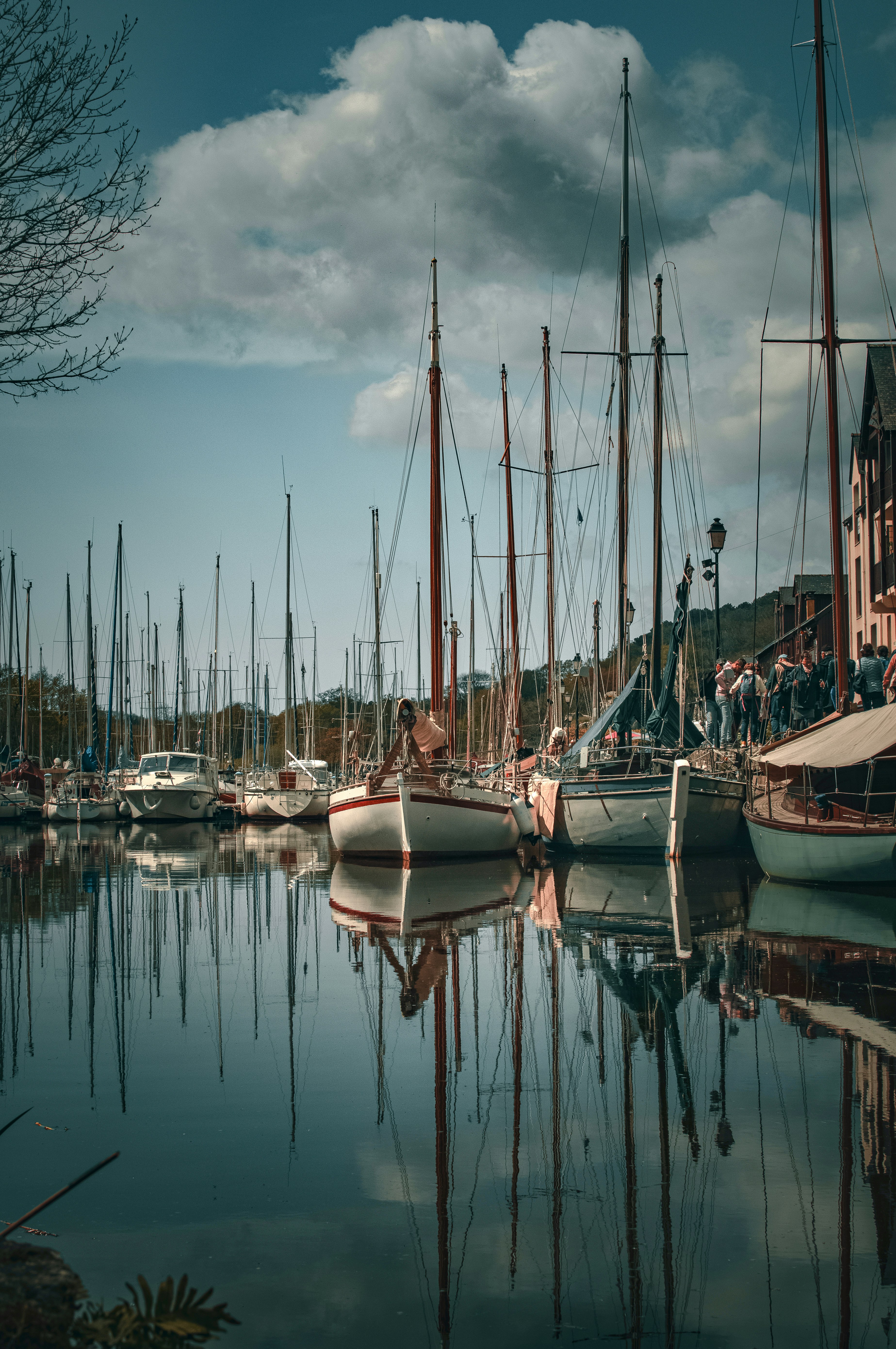 a harbor filled with lots of sailboats under a cloudy sky