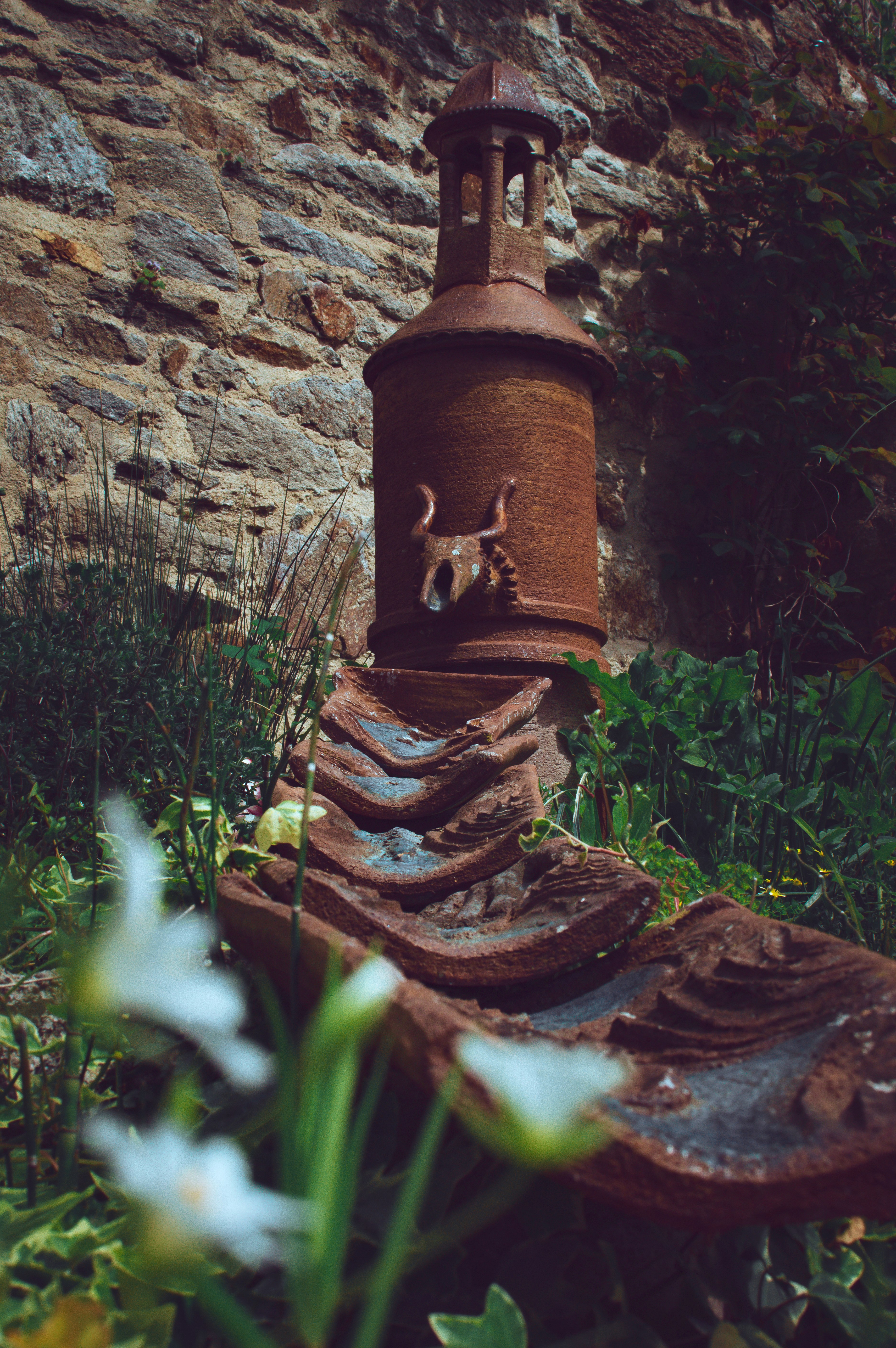 a rusted out water fountain in the middle of a garden